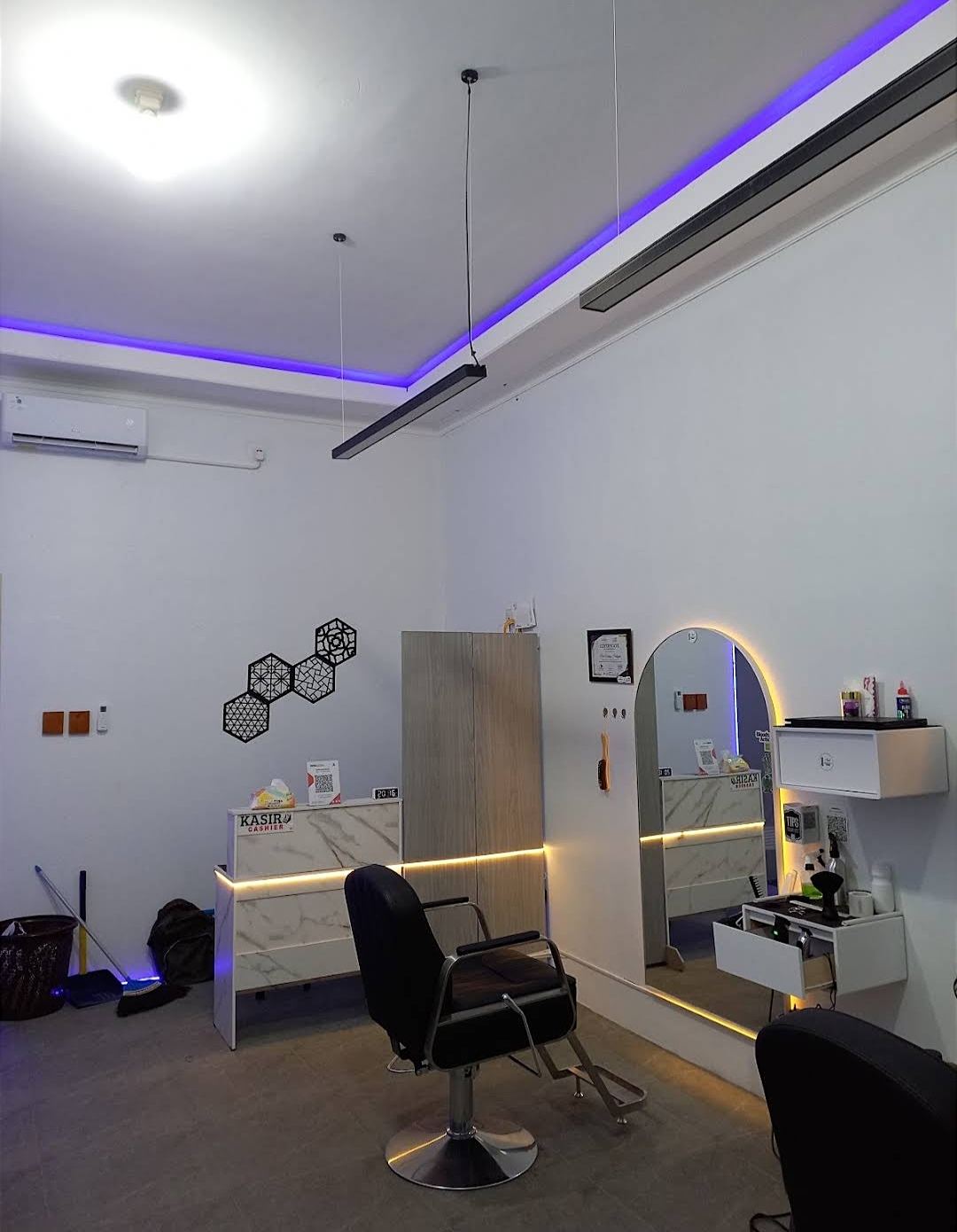Dua kursi barber dengan cermin lengkung berlampu kuning di NOOK Barbershop.