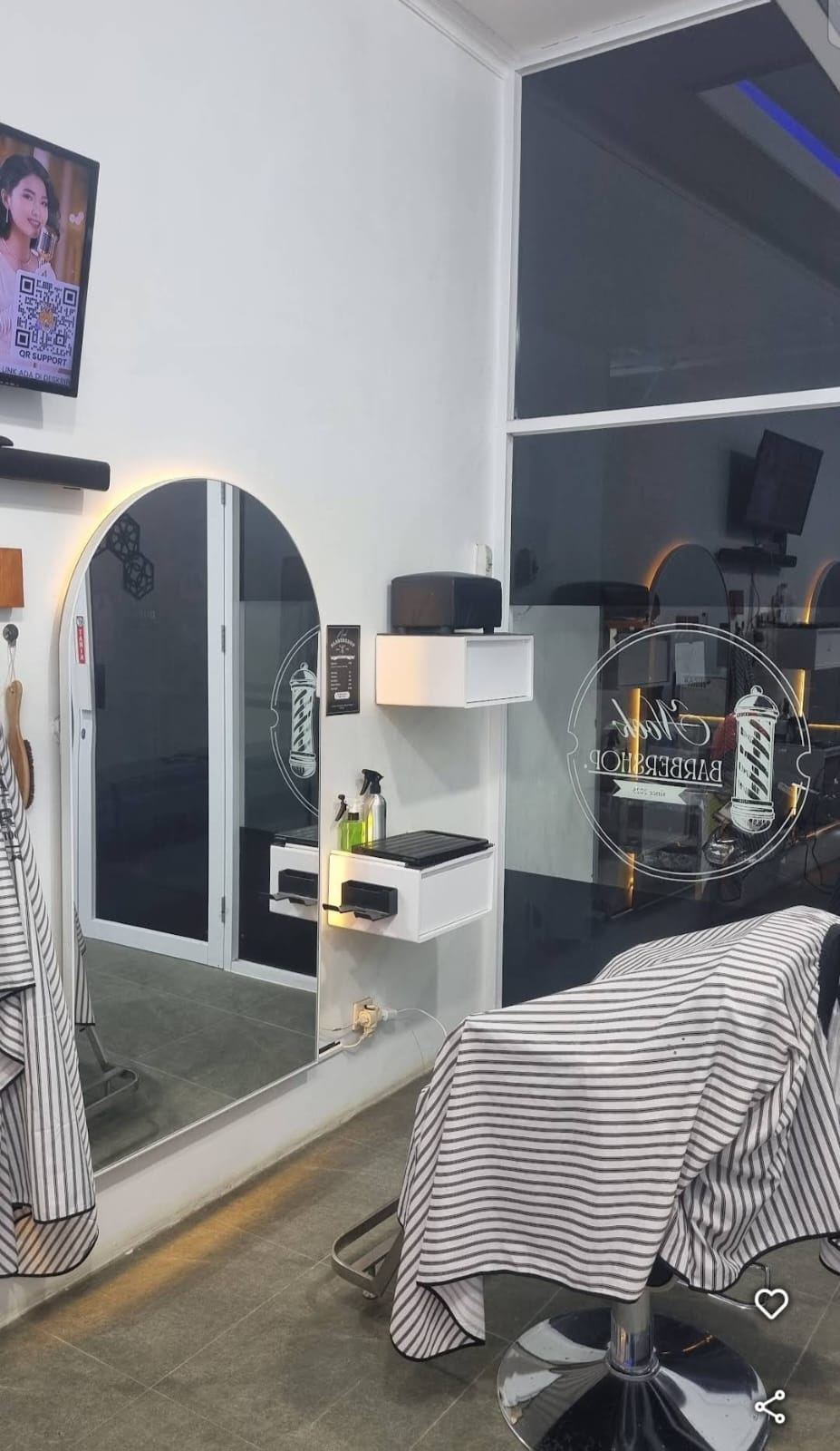 Meja kerja barber di depan cermin lengkung dengan lampu LED.