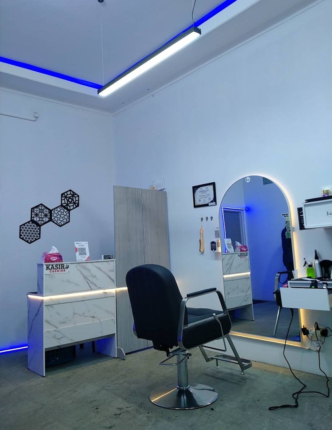 Interior NOOK Barbershop pada malam hari dengan lampu LED biru.